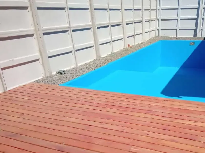 Piscina de hormigón premoldeado terminada, con deck de madera